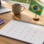 Calendário com datas de feriados nacionais do Brasil marcadas sobre uma mesa de trabalho.
